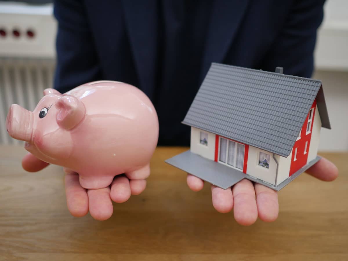Man holding piggy bank and miniature house